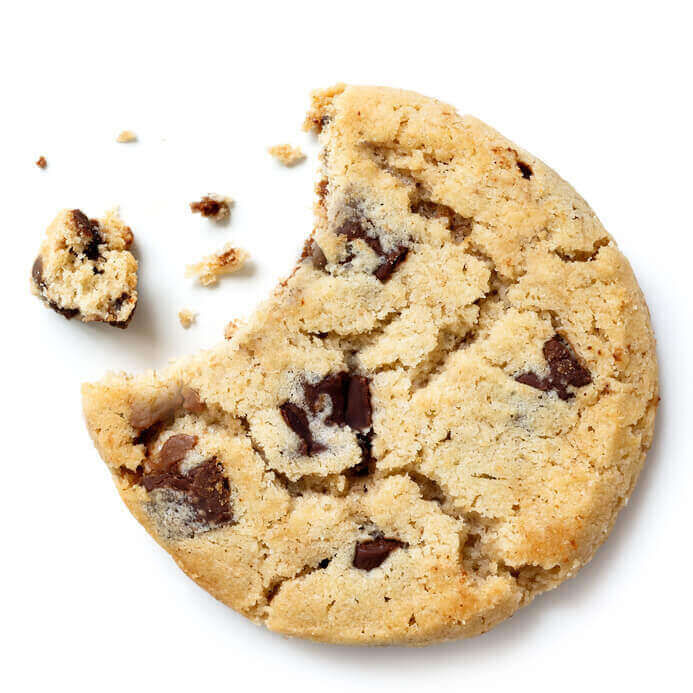 Light chocolate chip cookie, bite missing with crumbs from above.